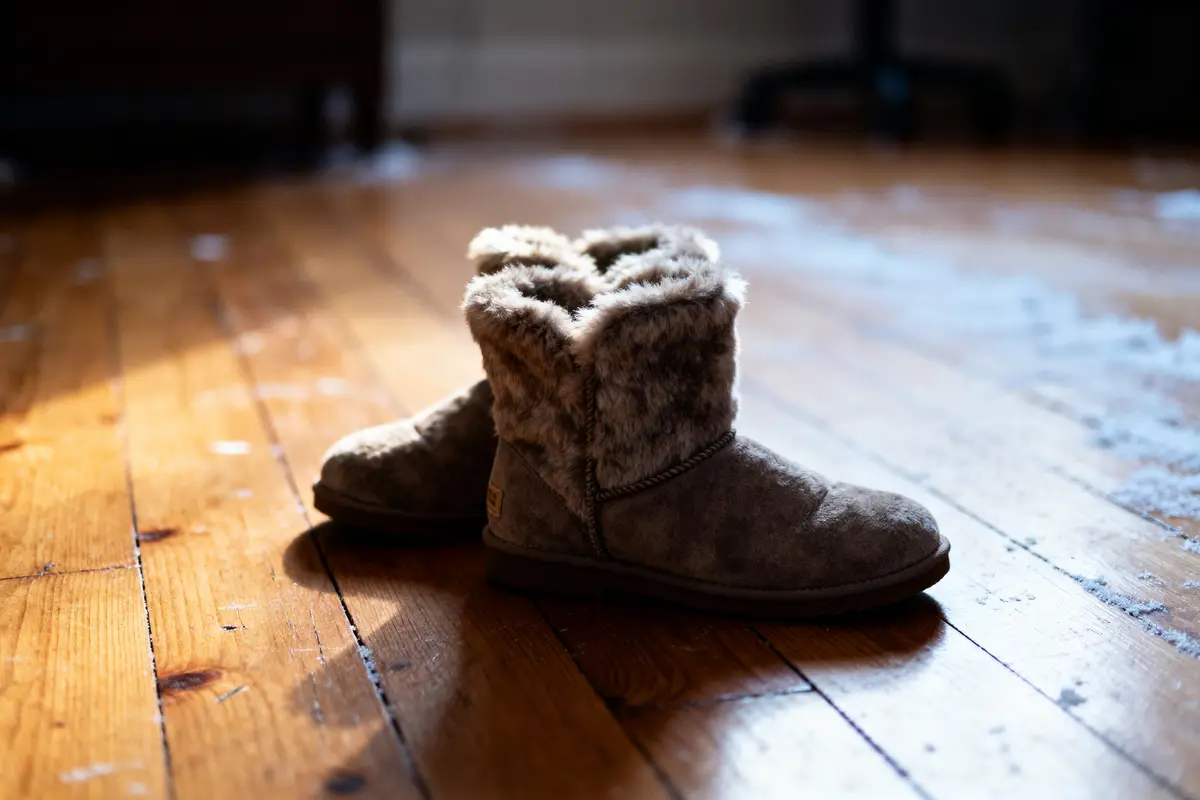 Fur-lined brown boots on a wooden floor with soft lighting.